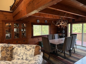 A wooden cabin interior with a dining table, chairs, a sofa, and a chandelier. - 4-bedroom PNW Woodland Lodge near Mt. St. Helens (Castle Rock)