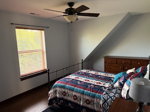 A bedroom with a bed, a wooden dresser, a ceiling fan, and a window with blinds. - 4-bedroom PNW Woodland Lodge near Mt. St. Helens (Castle Rock)