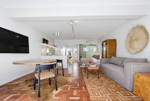 A modern living space with a dining area, a sofa, and a kitchen in the background. - Luxurious Studio on the Promenade (Cape Town)
