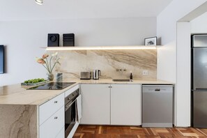 Eine moderne Küche mit Marmorarbeitsplatte, integrierten Geräten und Holzboden.