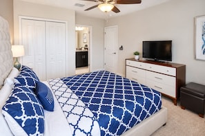 A bedroom with a bed, a dresser, a television, and a ceiling fan. - ChampionsGate 6BR Pool, Spa & Games (Four Corners)