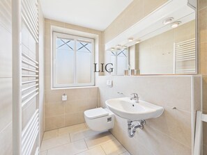 A modern bathroom with a toilet, sink, and window. - Holiday Apartment Uhlenkamp 4 (Langeoog)