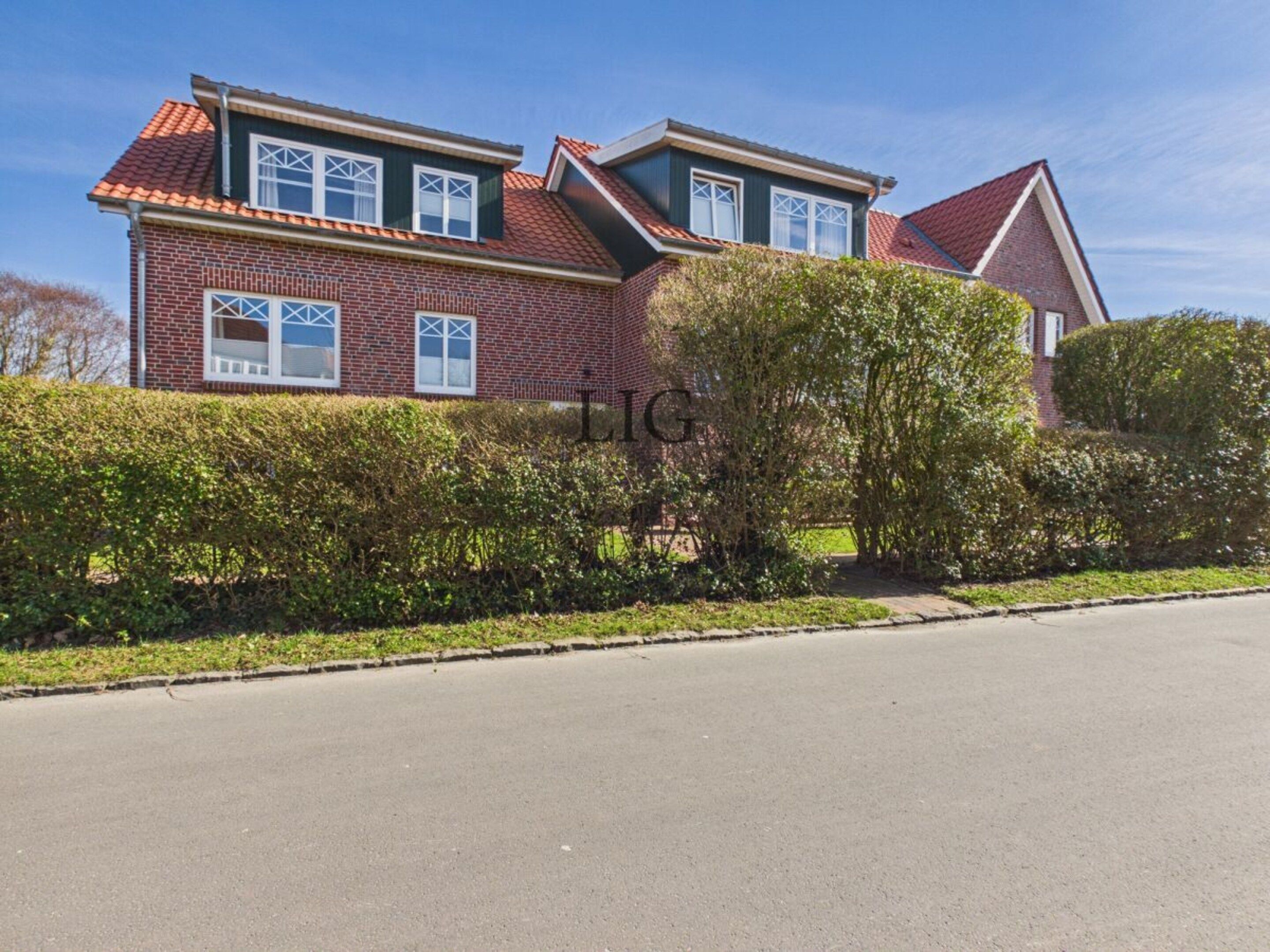 A two-story house with a brick facade, multiple windows, and a sloped roof.