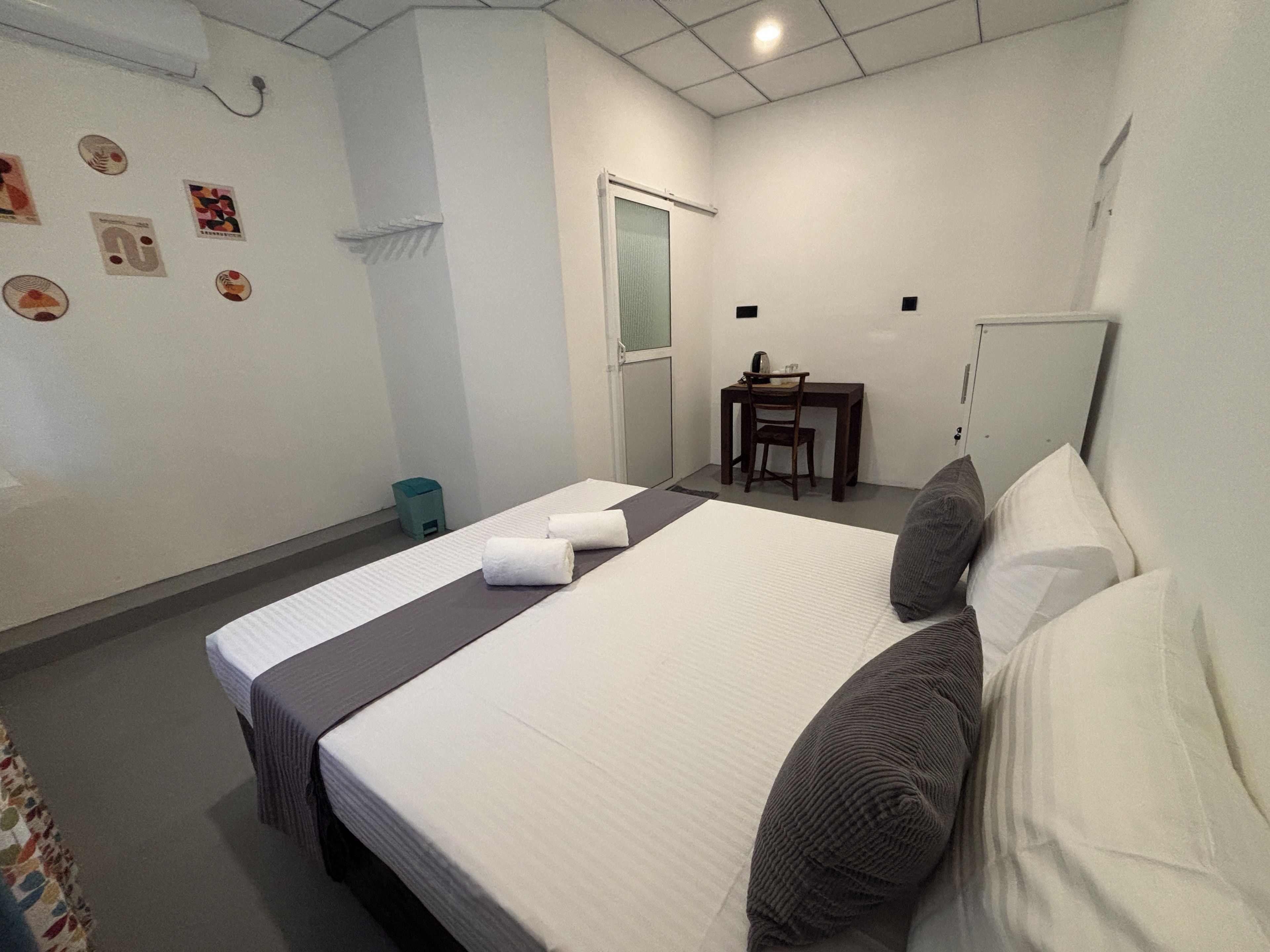 Una habitación de hotel con una cama, un escritorio, una silla y un cubo de basura pequeño.
