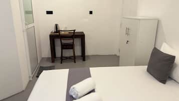 A hotel room with a bed, a desk, a chair, and a wardrobe.