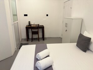 A hotel room with a bed, a desk, a chair, and a wardrobe. - The Cottage Weligama (Weligama)
