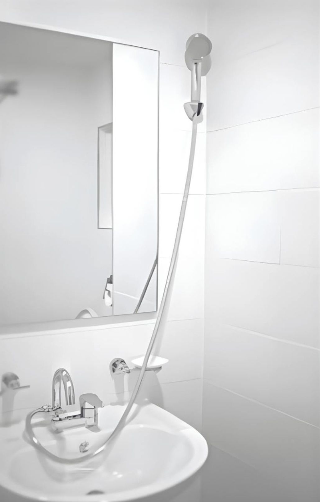 A bathroom with a white sink, a mirror, and a shower with a handheld showerhead.