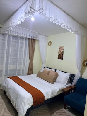 A bedroom with a bed, a chair, and a window with curtains. - Peaceful Syokimau Stay Near Airport (Mlolongo)