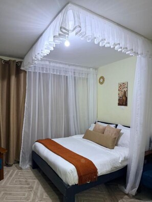A bed with a white canopy, beige pillows, and a brown throw blanket. - Peaceful Syokimau Stay Near Airport (Mlolongo)