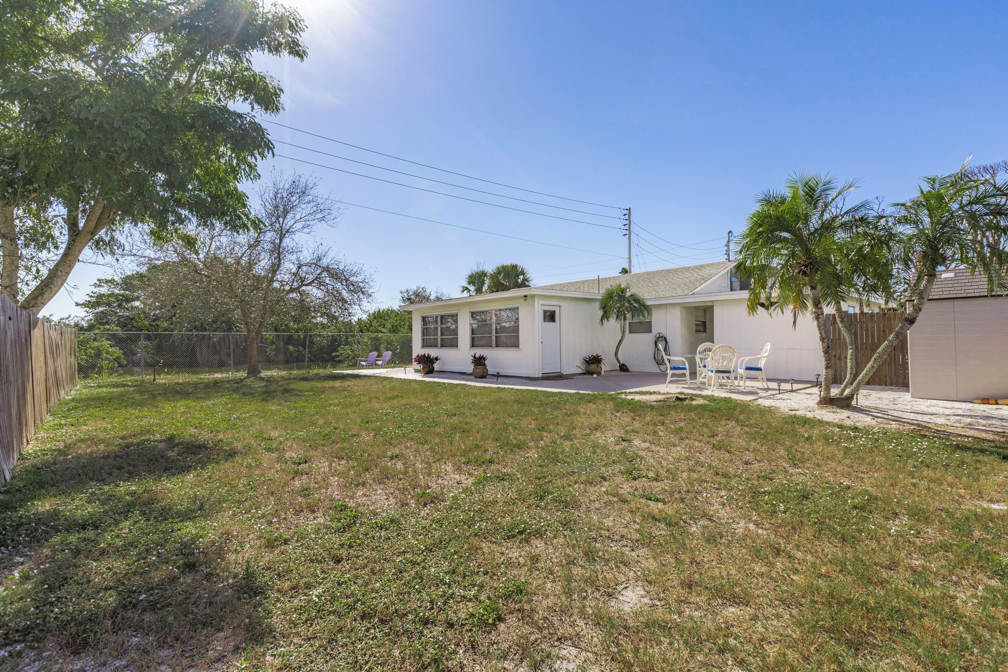 A single-story house with a small porch, a fenced yard, and a clear sky.