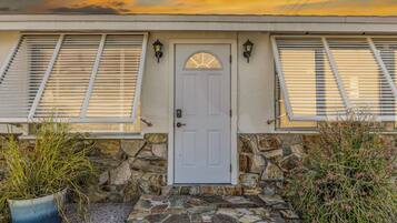 A house with a stone facade, a white door, and shutters on the windows.