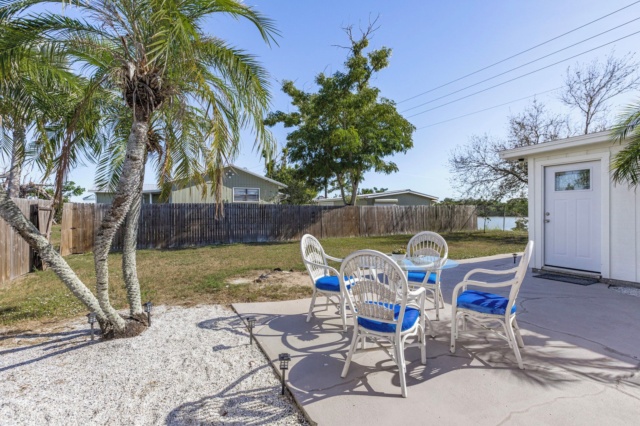 A patio with outdoor furniture, a palm tree, and a wooden fence.