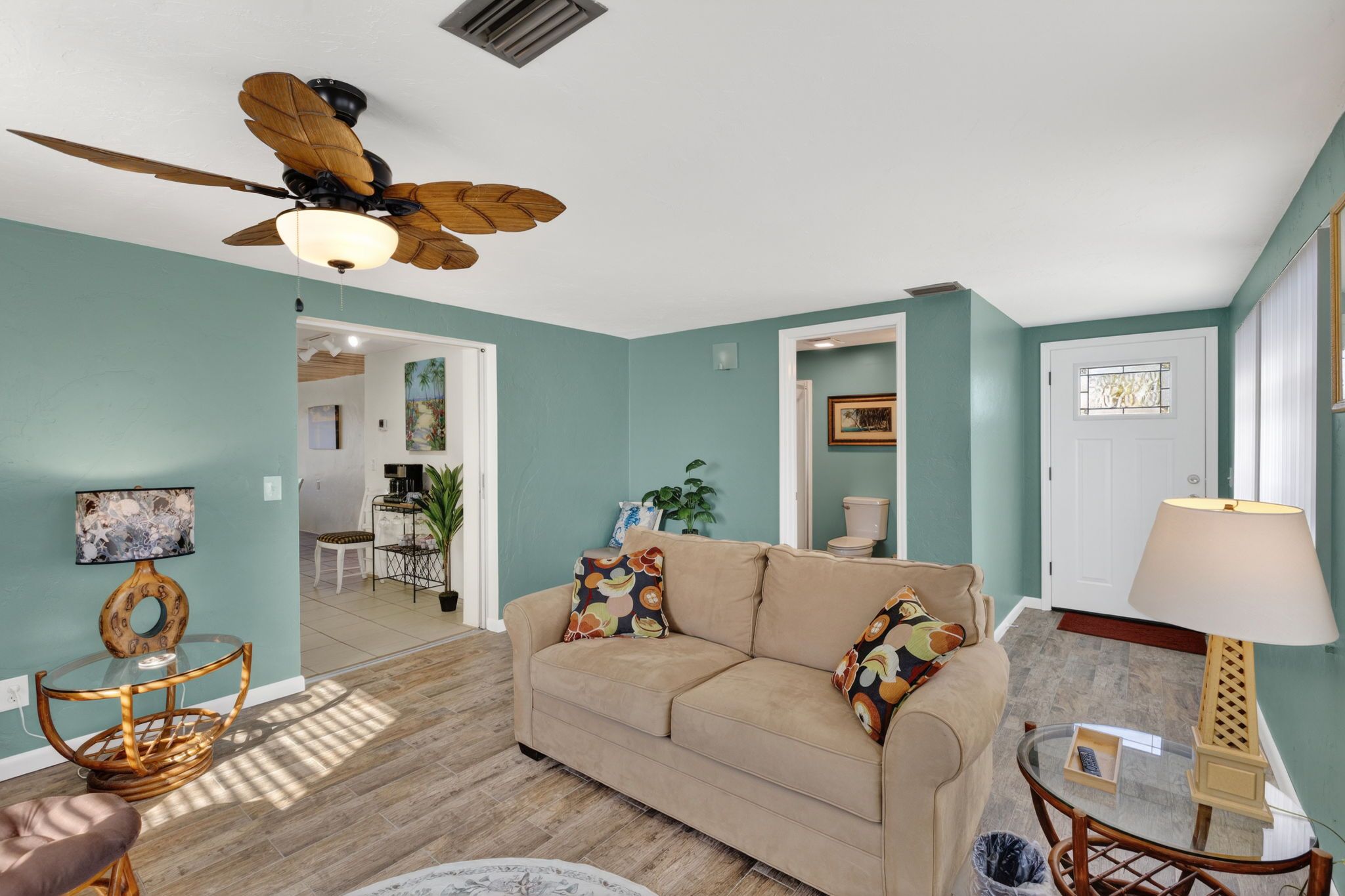 A living room with a beige sofa, a ceiling fan, and a wooden coffee table.