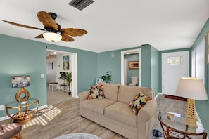 A living room with a beige sofa, a ceiling fan, and a wooden coffee table. - Lemon Bay Fishing & Beach Home (Englewood)