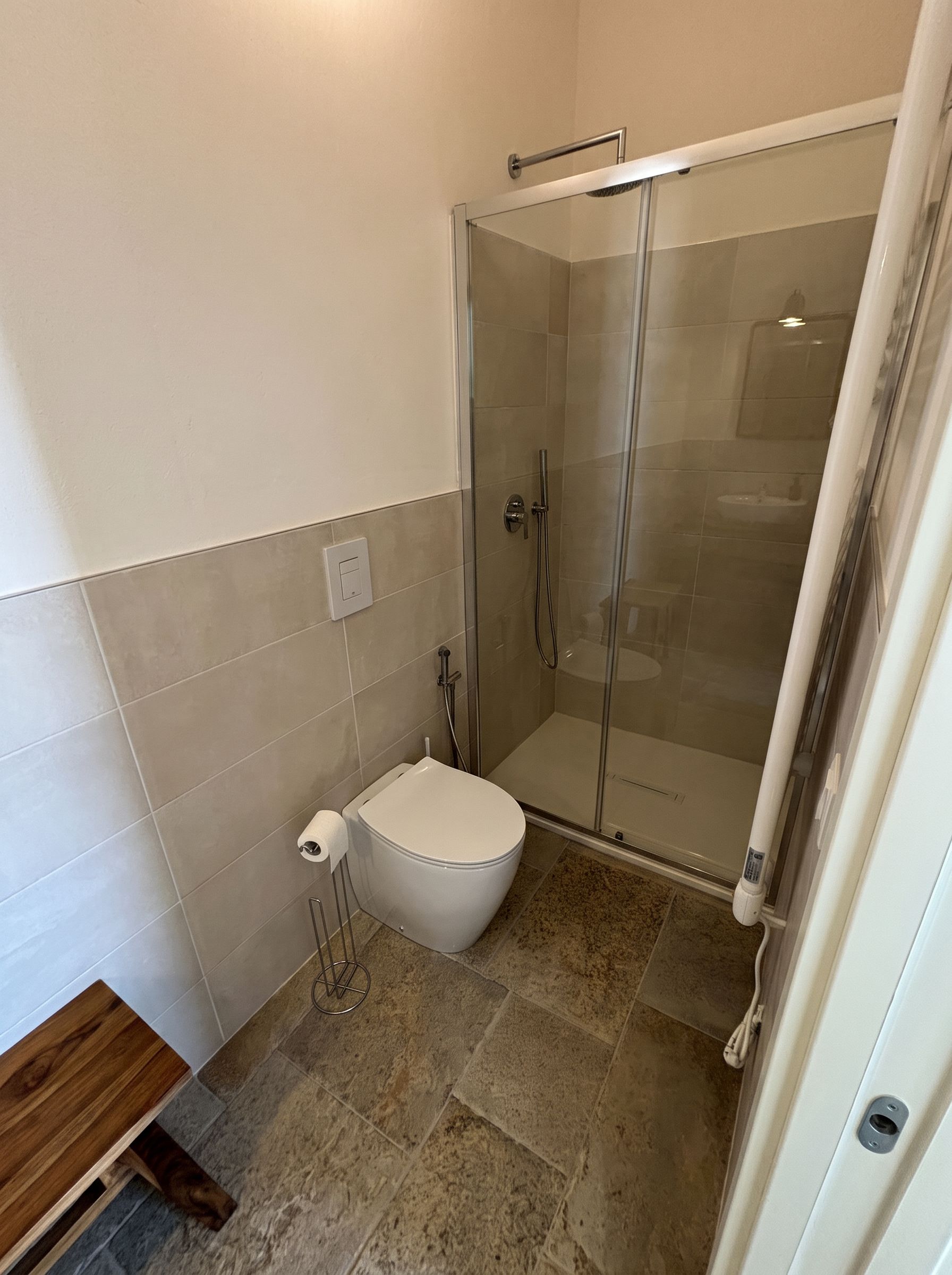 Ein Badezimmer mit Toilette, einer Duschkabine und einem Handtuchhalter.