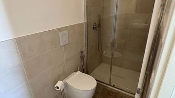 Ein Badezimmer mit Toilette, einer Duschkabine und einem Handtuchhalter.