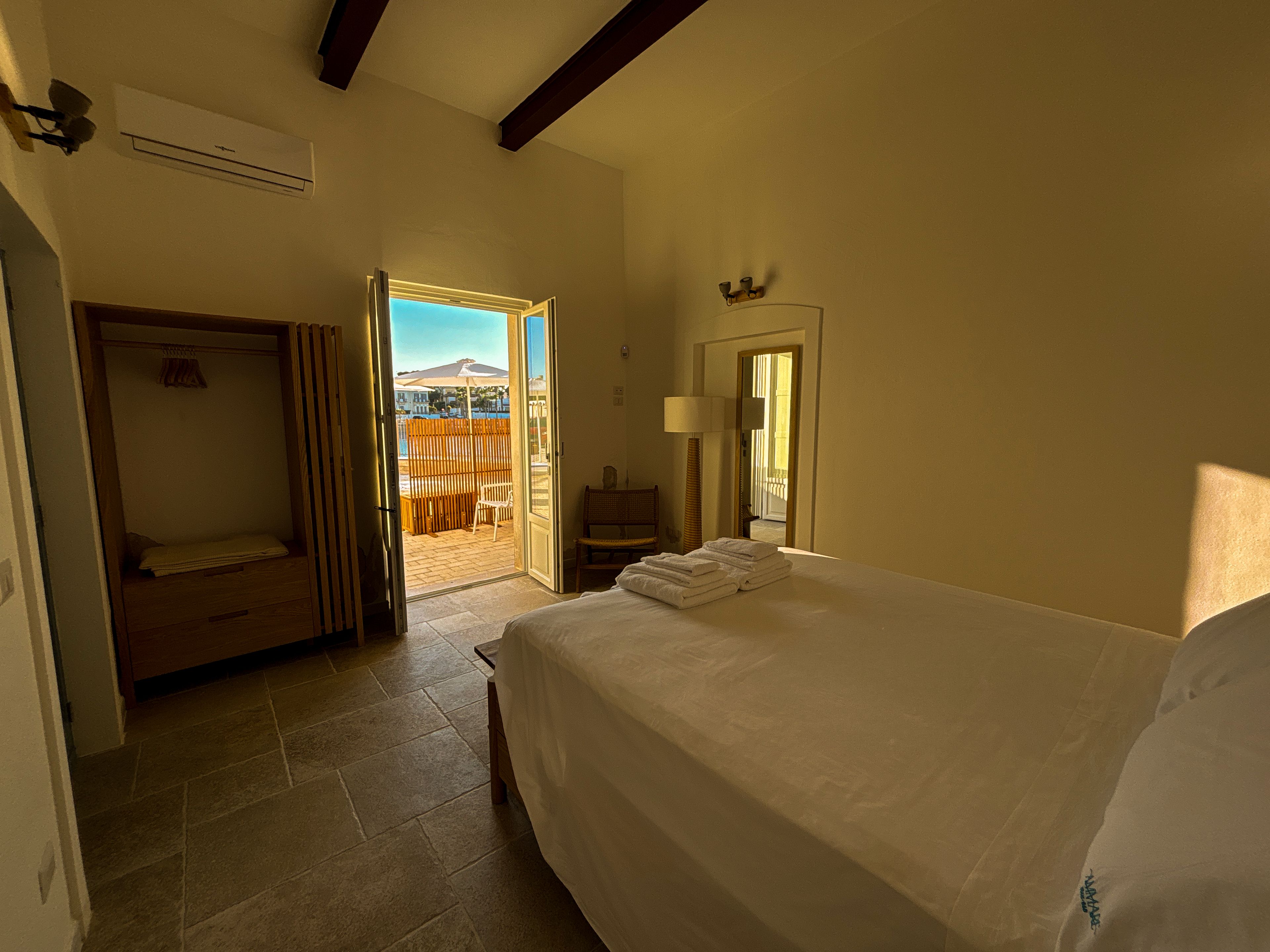 Ein Hotelzimmer mit Bett, Stuhl, Schreibtisch und Blick nach draußen.