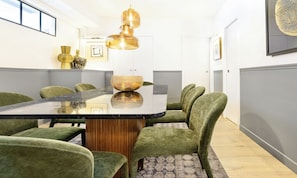 A conference room with a glass-top table, green upholstered chairs, a wooden base, and a hanging pendant light. - LUXURY CENTRAL PARIS APARTMENT WITH AC & HIGH-END BEDDING (Paris)