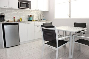 A compact kitchen with white cabinets, a microwave, a dishwasher, and a dining table with chairs. - Casa Iliria 1: cozy 1-bedroom apartment with AC in charming Boquerón (Boquerón)