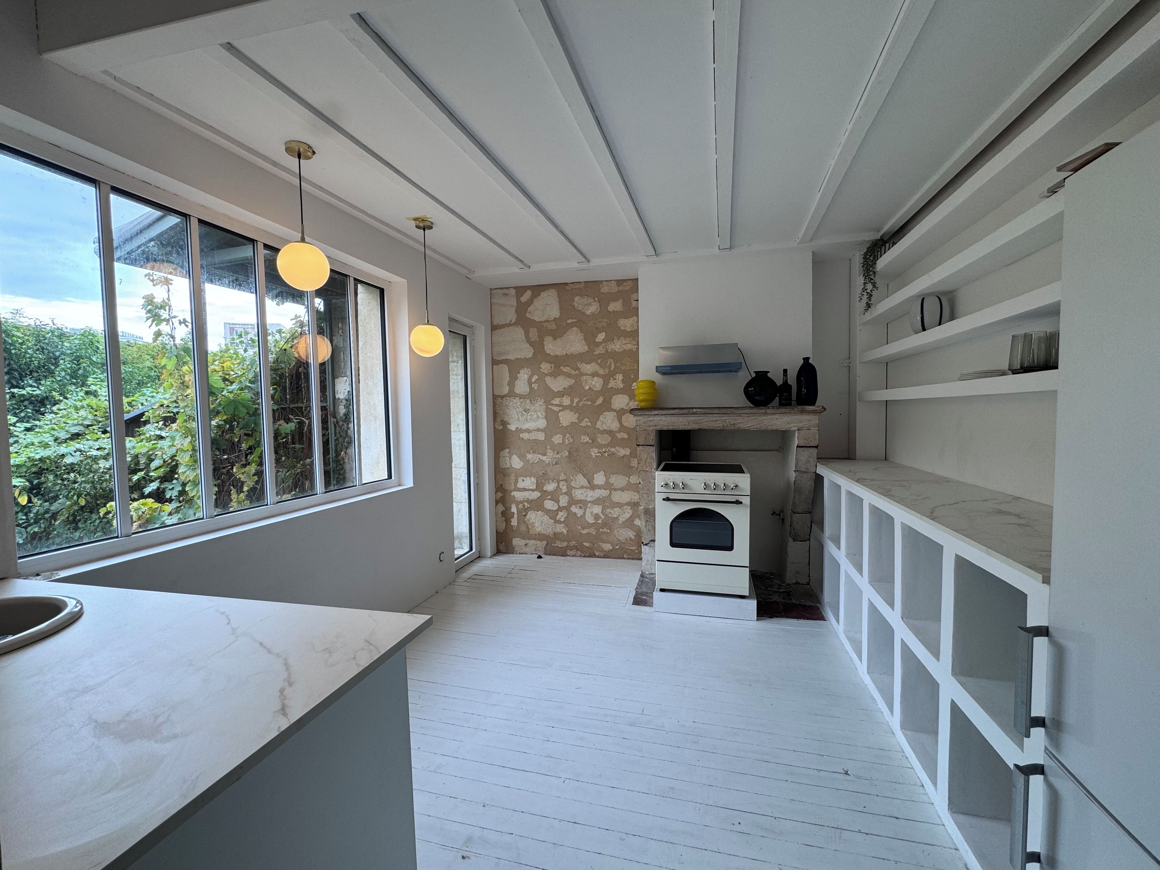 A kitchen with a stone wall, a built-in oven, and a window overlooking greenery.