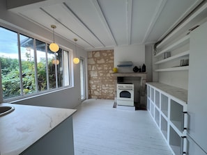 A kitchen with a stone wall, a built-in oven, and a window overlooking greenery. - Bordeaux-style townhouse with a garden, a 5-minute walk from the train station (Bordeaux)