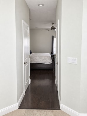 A narrow hallway leading to a bedroom with a bed, a ceiling fan, and a window with curtains. - A home away from home! A very spacious and comfortable place to relax! (Orlando)