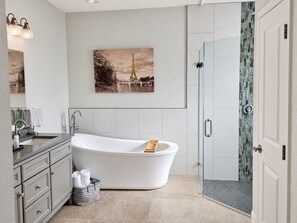 A modern bathroom with a freestanding bathtub, a glass shower enclosure, and a large mirror. - A home away from home! A very spacious and comfortable place to relax! (Orlando)