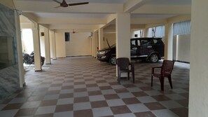 A covered parking area with a checkered floor, a ceiling fan, and a few plastic chairs. - MMR RESIDENCY (Tirupati)