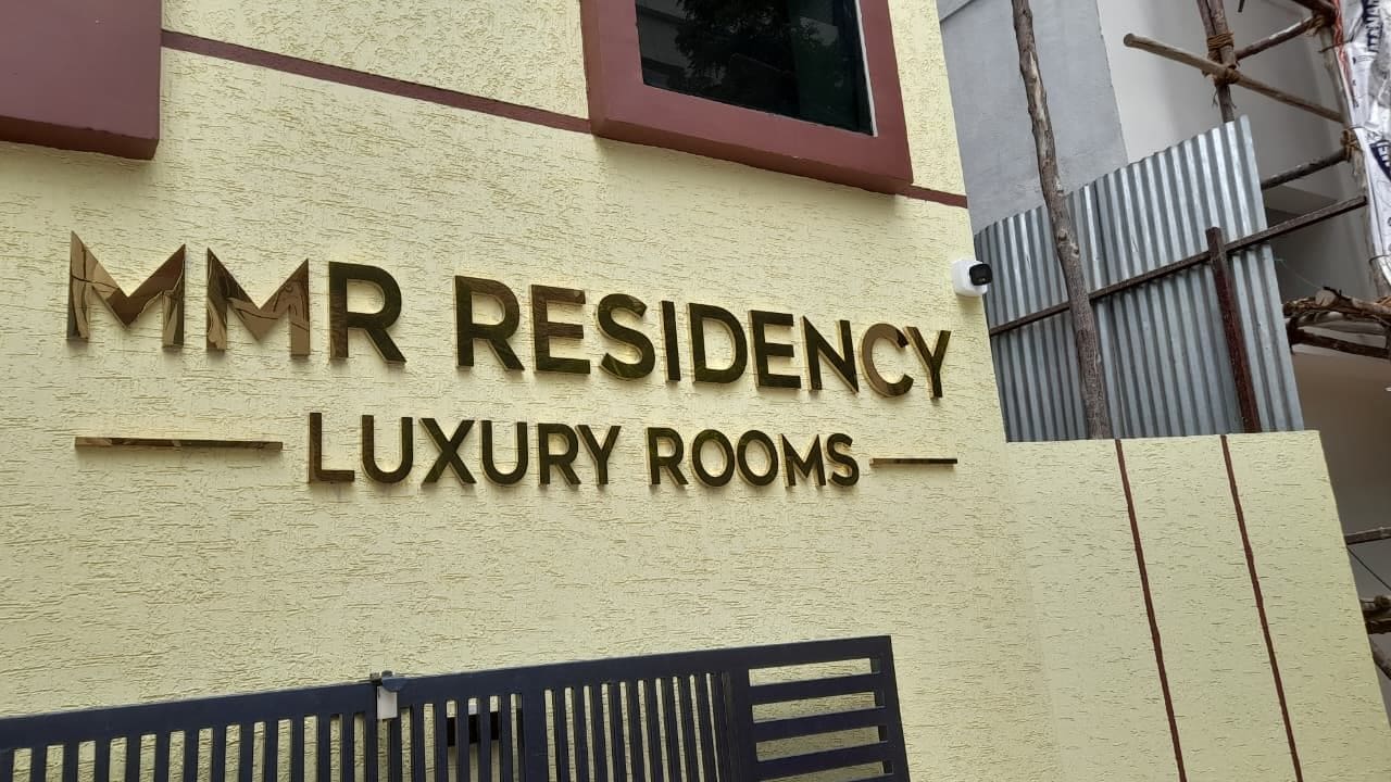 Une enseigne indiquant « MMR Residency, chambres de luxe » sur la façade d’un immeuble.