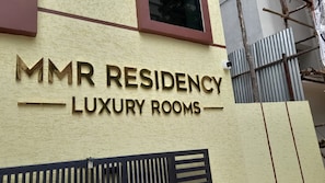 Un cartell amb la inscripció 'MMR Residency Luxury Rooms' a la façana d'un edifici.