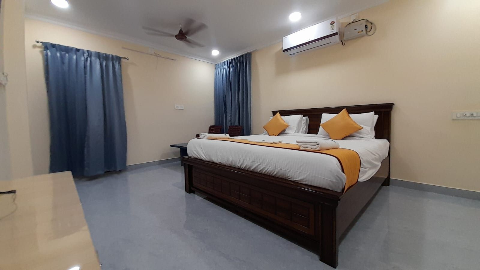 Une chambre à coucher avec un lit, des rideaux, un climatiseur et un ventilateur de plafond.