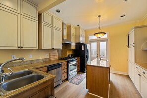 A kitchen with a double sink, stainless steel appliances, and wooden cabinets. - Victorian 3BR with Jetted Tub + Fireplaces - Central District (Seattle)