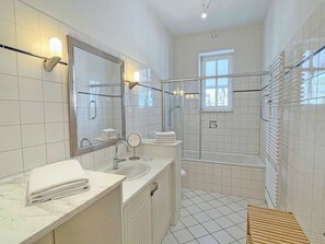 A modern bathroom with a large mirror, two sinks, a shower, and a toilet. - in the House on the Dune (Binz)