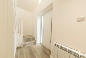 A hallway with a radiator, a door, and a bench. - A Little Home of Your Own in Poulton — Gated Entrance & Parking (Poulton-le-Fylde)
