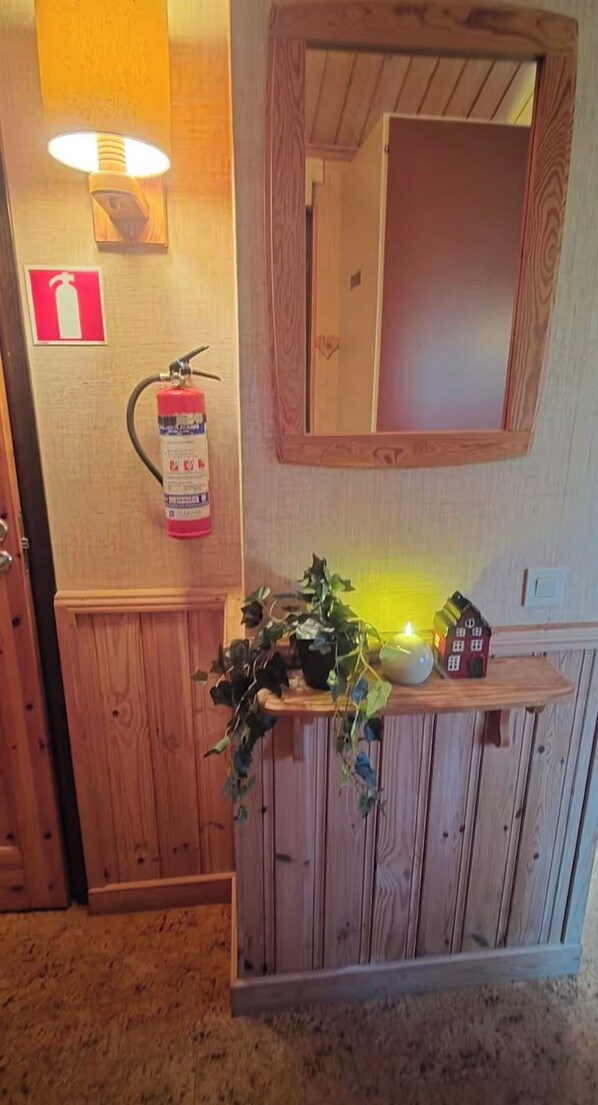 Un taulell de recepció de fusta amb un mirall, un extintor i una planta en test.