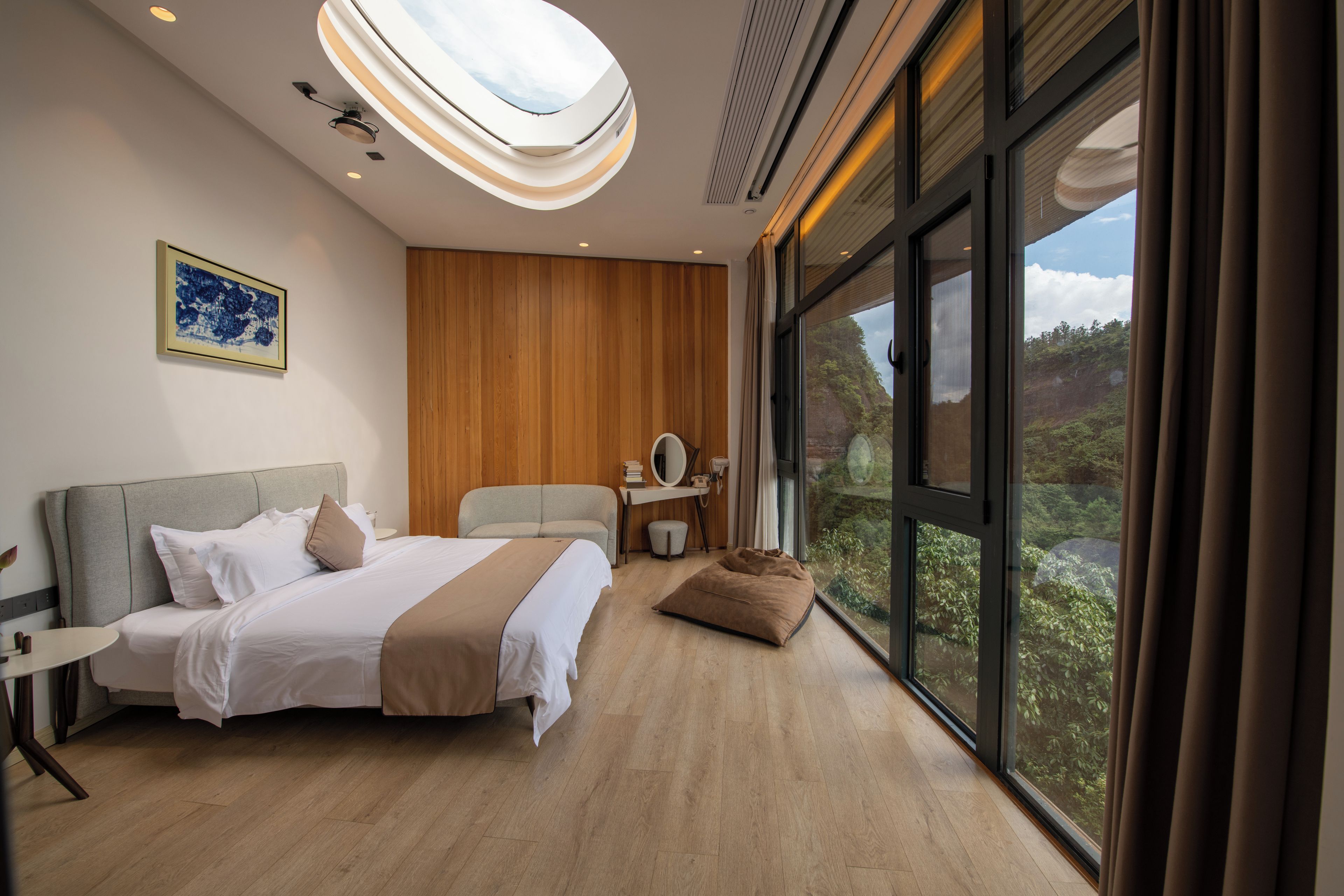 Habitación de hotel moderna con una cama grande, un escritorio, una silla y vistas al exterior.