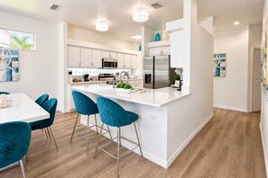 A modern kitchen with white cabinetry, stainless steel appliances, and a central island with bar stools. - Lakefront near Disney: Pool + LEGO game room (Kissimmee)