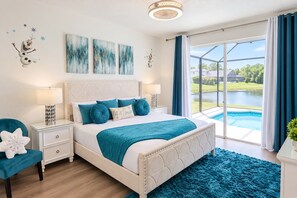 A bedroom with a bed, a nightstand, a chair, a large window with a view of a swimming pool, and artwork on the wall. - Lakefront near Disney: Pool + LEGO game room (Kissimmee)