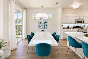 A modern kitchen with white cabinets, stainless steel appliances, and a central island with teal chairs. - Lakefront near Disney: Pool + LEGO game room (Kissimmee)