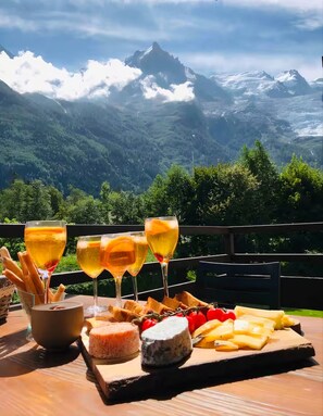 A table with a cheese platter, glasses of wine, and baguettes against a mountain backdrop. - Chamonix Gaillands (Chamonix-Mont-Blanc)
