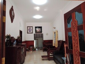 A living room with a sofa, a wooden cabinet, a clock, and a decorative mirror. - 3-bedroom house in beautiful Siem Reap with cool AC (Krong Siem Reap)