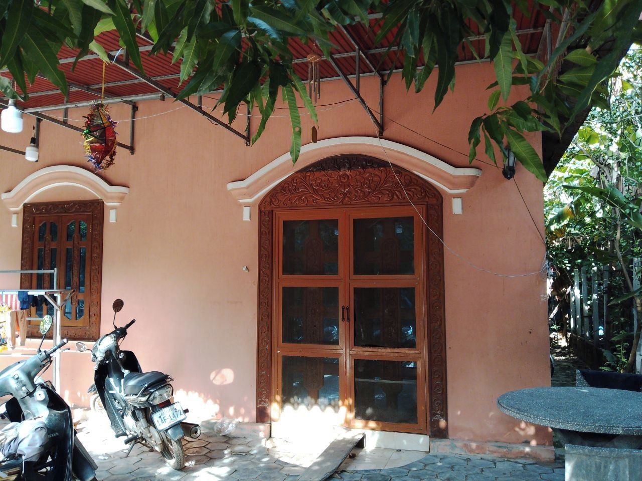 A building with a large wooden door, two parked scooters, and a tiled floor.