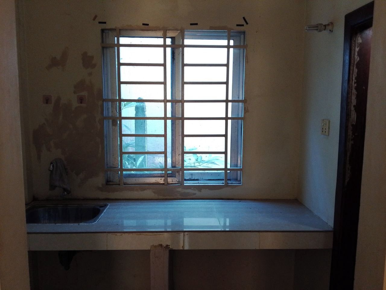 A kitchen with a window, a sink, and a door.