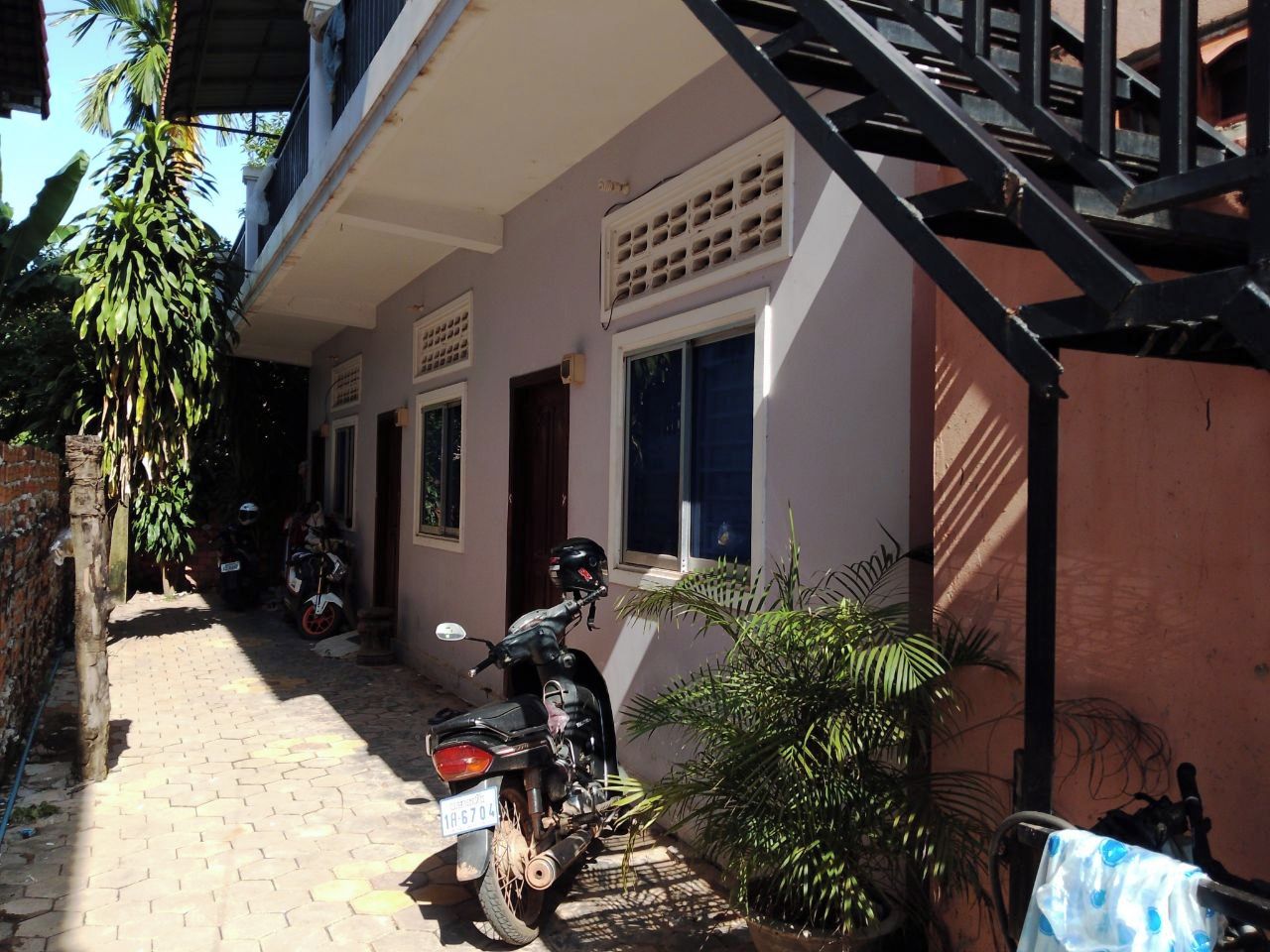 A residential building with a staircase, a parked motorcycle, and a potted plant.