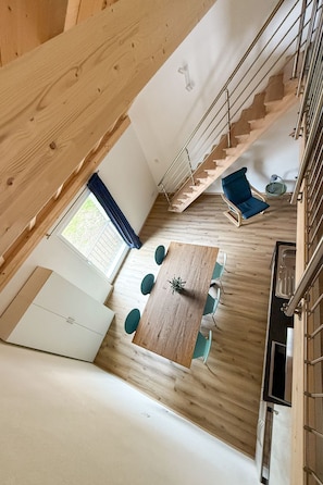 Un intérieur moderne avec un plancher en bois, une table à manger avec des chaises, un escalier et un canapé bleu.