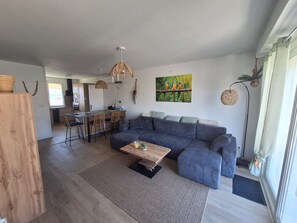 A modern living room with a sectional sofa, a coffee table, and a dining area with chairs. - HOUSE IN AN IDEAL LOCATION IN THE CENTER OF MARENNES (Marennes-Hiers-Brouage)