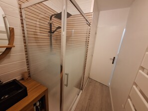 A shower with a glass door, a wooden floor, and a white door to the right. - HOUSE IN AN IDEAL LOCATION IN THE CENTER OF MARENNES (Marennes-Hiers-Brouage)