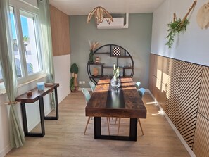A modern dining area with a wooden table, chairs, and a decorative plant centerpiece. - HOUSE IN AN IDEAL LOCATION IN THE CENTER OF MARENNES (Marennes-Hiers-Brouage)