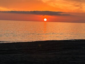 Ein Sonnenuntergang über einem ruhigen Meer mit deutlicher Horizontlinie.