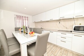 A modern kitchen with white cabinets, a marble backsplash, and a built-in microwave. - Holiday home Lucia 5 minutes’ walk from Old Town in Trogir with private pool (Trogir)